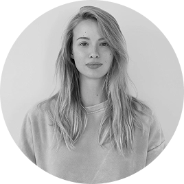 Zwart-witportret van een jonge vrouwelijke medewerkster tegen een zachtgroene achtergrond, gepresenteerd in een strakke ronde lijst.