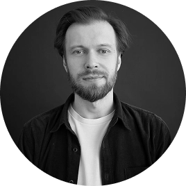 Zwart-witportret van een bebaarde man in zakelijke kleding, afgebeeld in een ronde lijst tegen een minimalistische achtergrond.