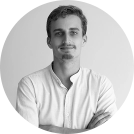 Zwart-witportret van een mannelijk teamlid met de armen over elkaar, weergegeven in een ronde lijst tegen een sobere groene achtergrond.