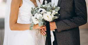 Bruid en bruidegom met een bruidsboeket van witte bloemen en groen, vastgelegd in een intiem en romantisch moment.