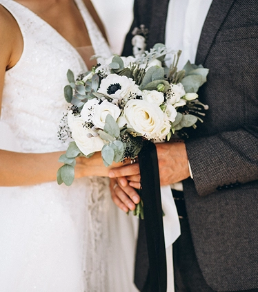 Bruid en bruidegom met een bruidsboeket van witte bloemen en groen, vastgelegd in een intiem en romantisch moment.
