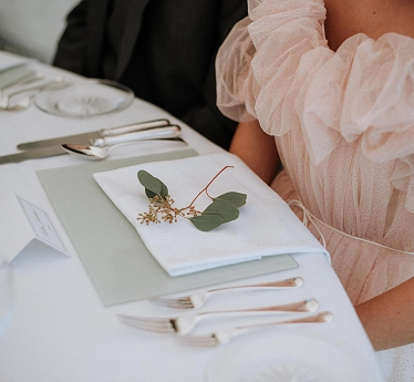 Een elegante tafelaankleding voor een bruiloft, met menukaart, bestek en subtiele decoraties, die de verfijnde details van de receptie benadrukken.